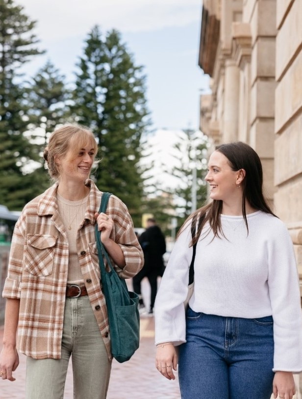 Two undergraduate students walking and talking near Fremantle station.