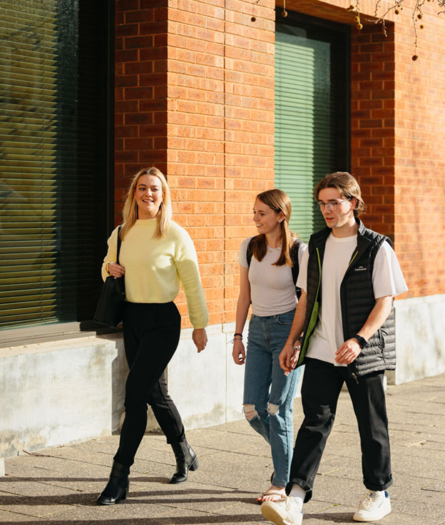 Group of 3 Notre Dame students walking outside of Nursing & Midwifery building on the Fremantle Campus.