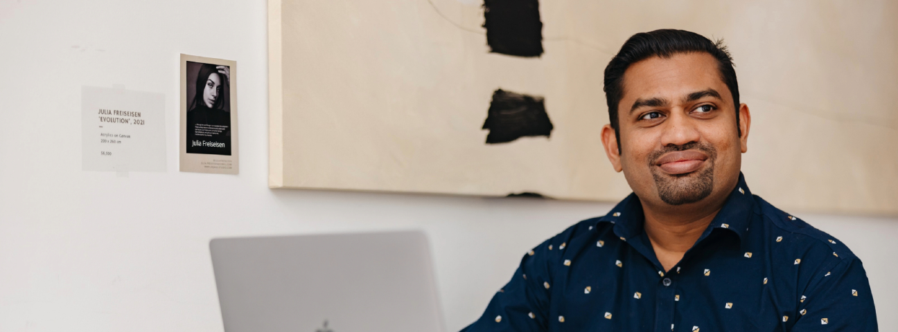 Subin Daniel, student in the Graduate Diploma of Business program sitting at a table with a laptop looking off into the distance