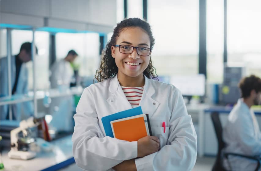 Student studying medicine dressed in a white lab coat and holding textbooks