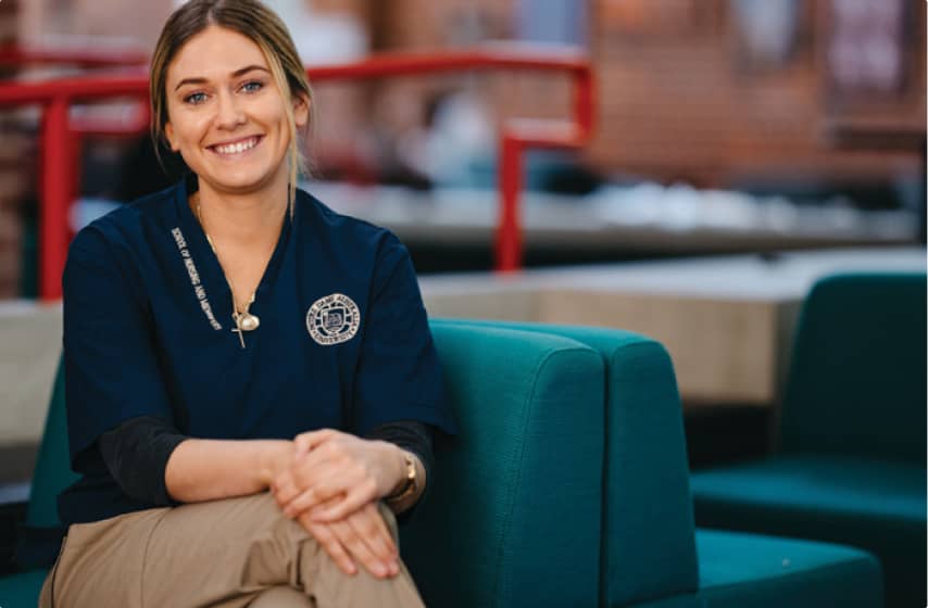 Student studying Nursing & Midwifery sitting on a couch smiling