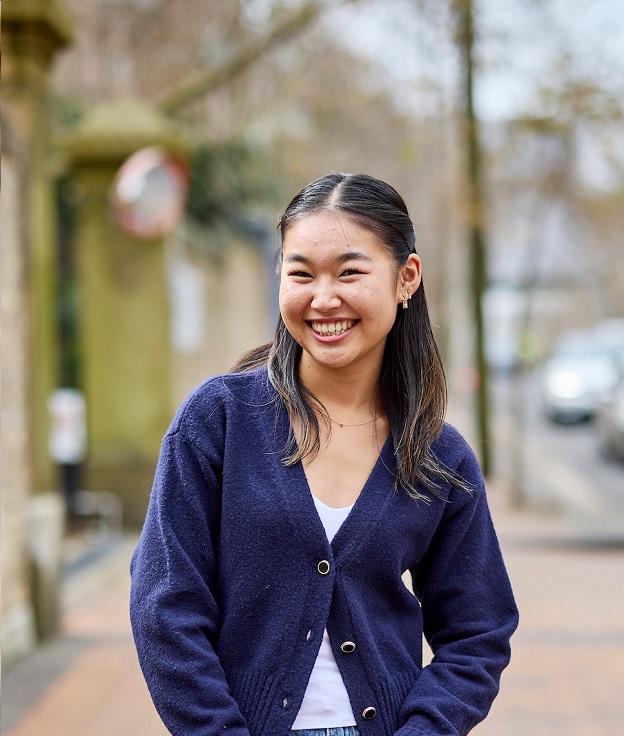Student standing outside Broadway Campus entrance smiling