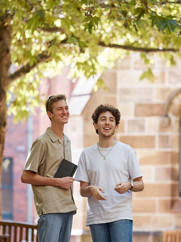 Two male Notre Dame students smiling and talking outside of the campus chapel  