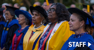 Link to staff page over Nulungu staff standing side by side at a graduation ceremony.